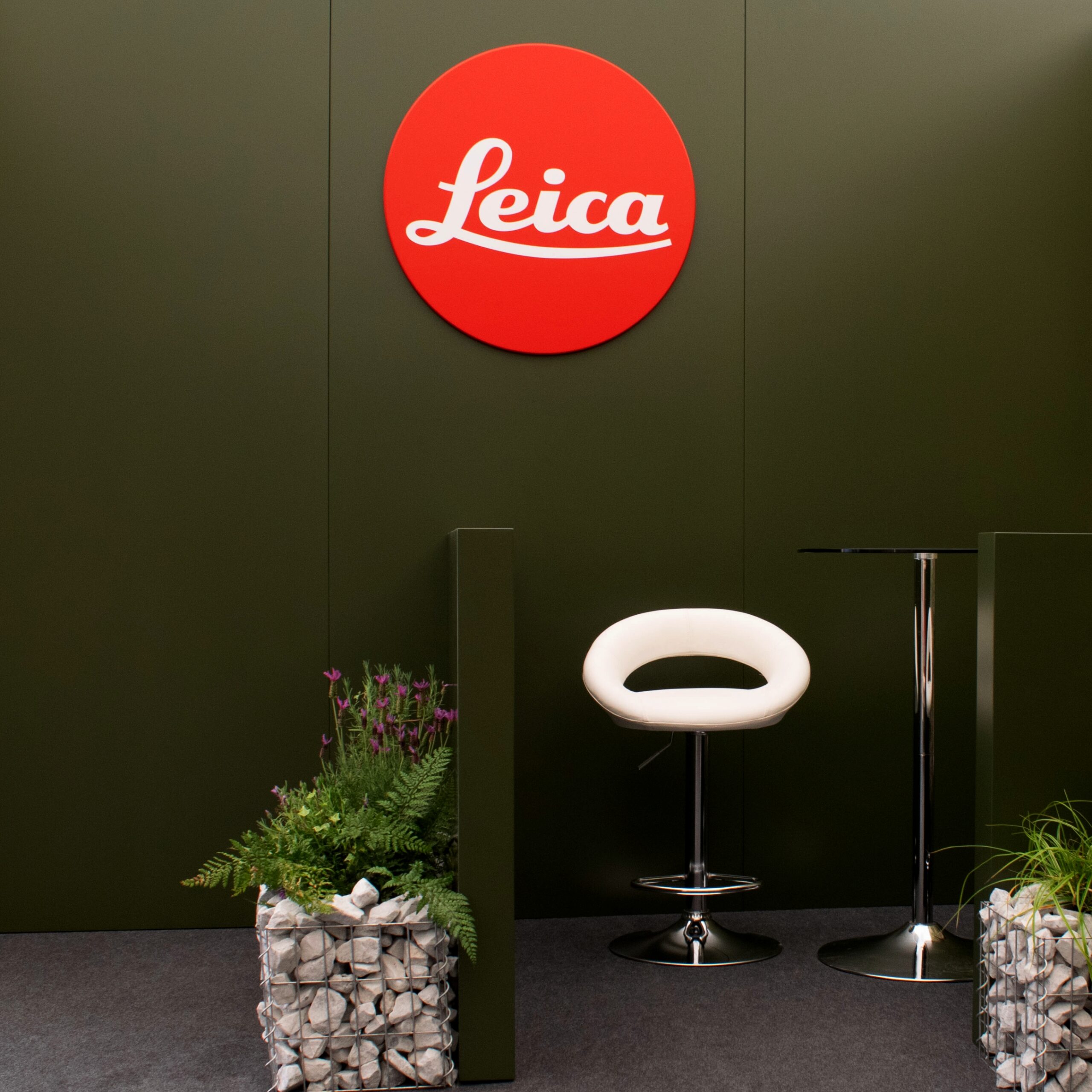 Bespoke Leica exhibition stand combining branded graphics with a dedicated seating area, creating an inviting space for visitor engagement and premium spatial experience.