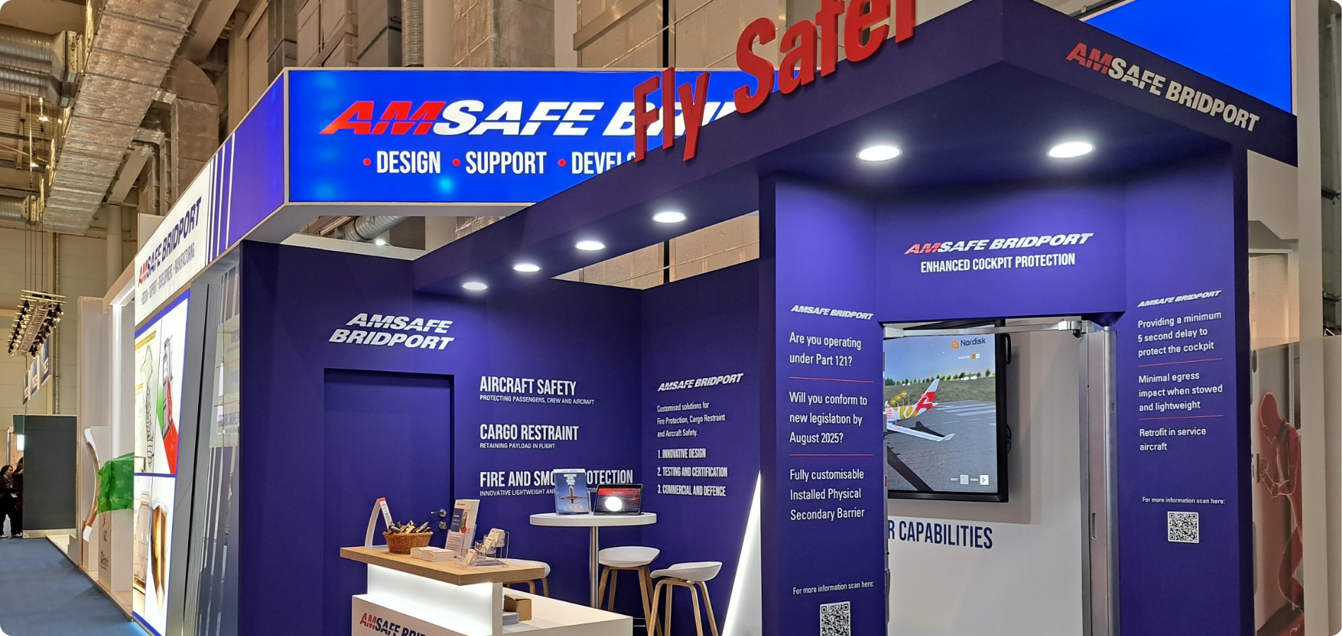 AmSafe Bridport's bespoke exhibition stand design featuring an interactive screen and brand messaging across the stand walls.